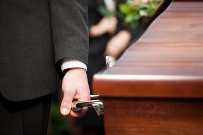 Religion, death and dolor - coffin bearer carrying casket at funeral to cemetery